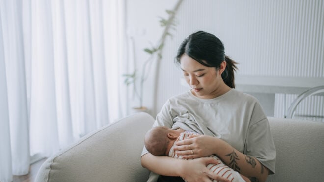 Asian Chinese young mother breastfeeding baby girl at home