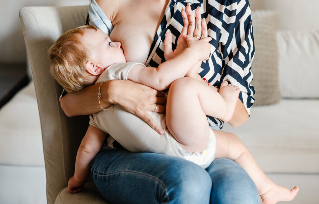 Young mother breastfeeding her baby boy at home
