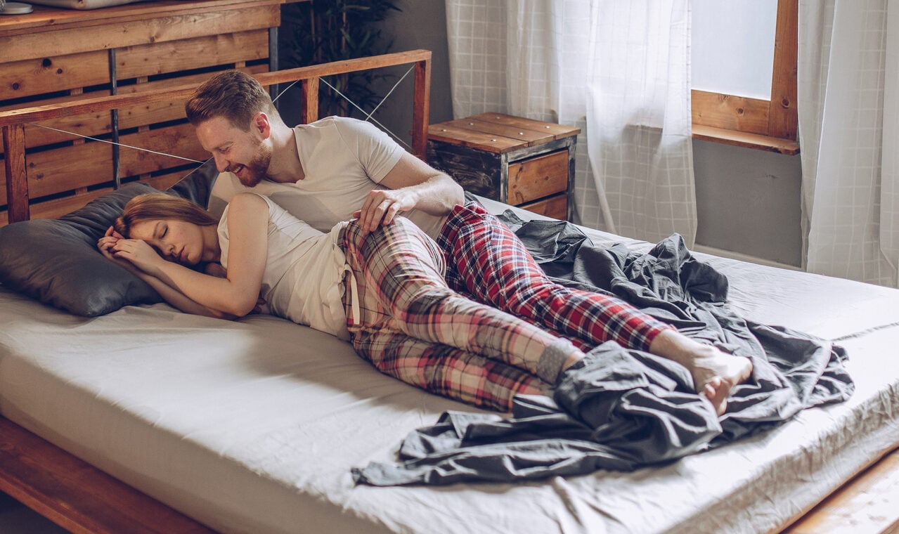 Man and woman, young heterosexual couple in bedroom, relaxing in bed,