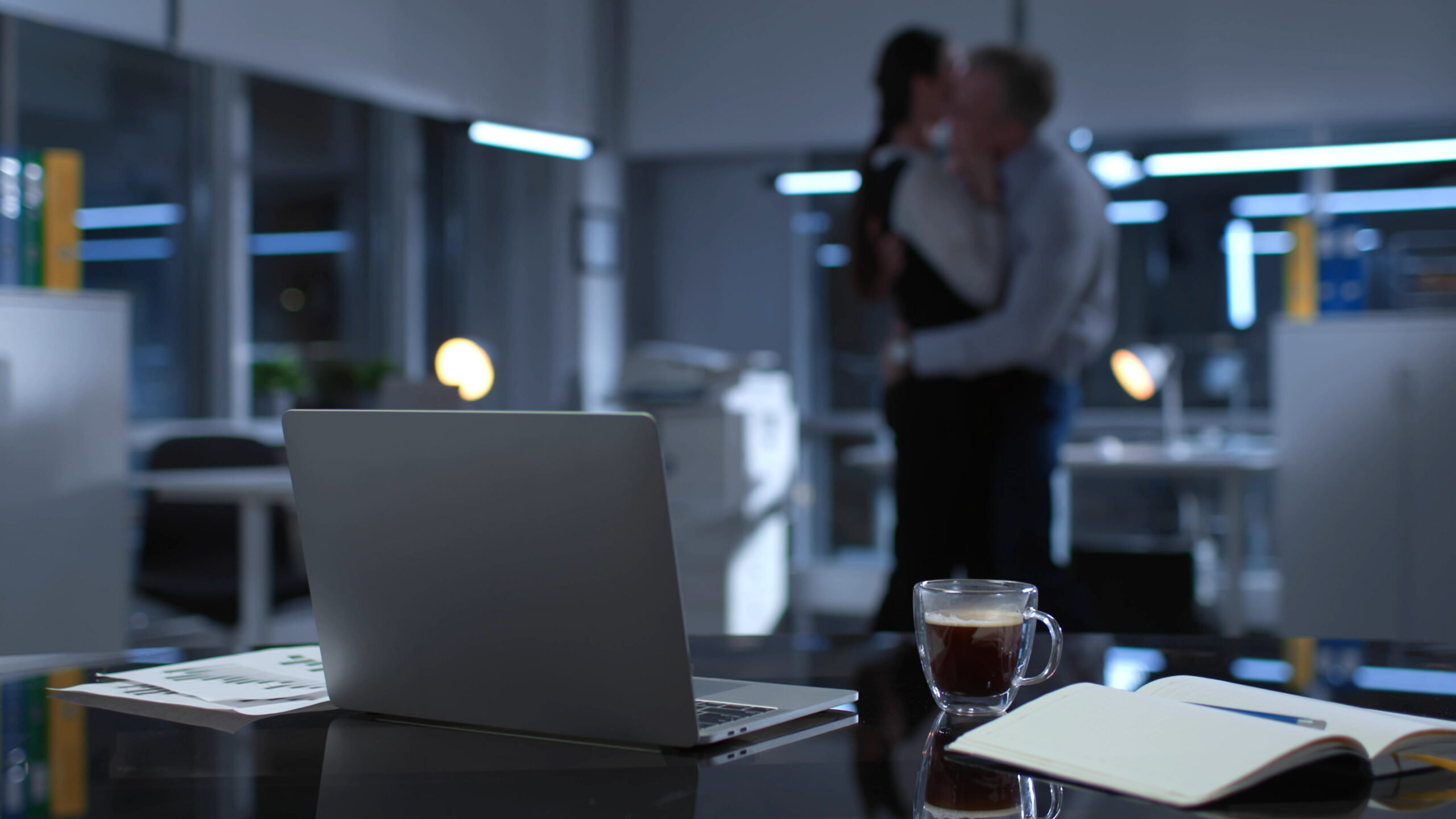 Blurred shot of colleagues hugging and making out late in empty office. Business people having affair at night at workplace