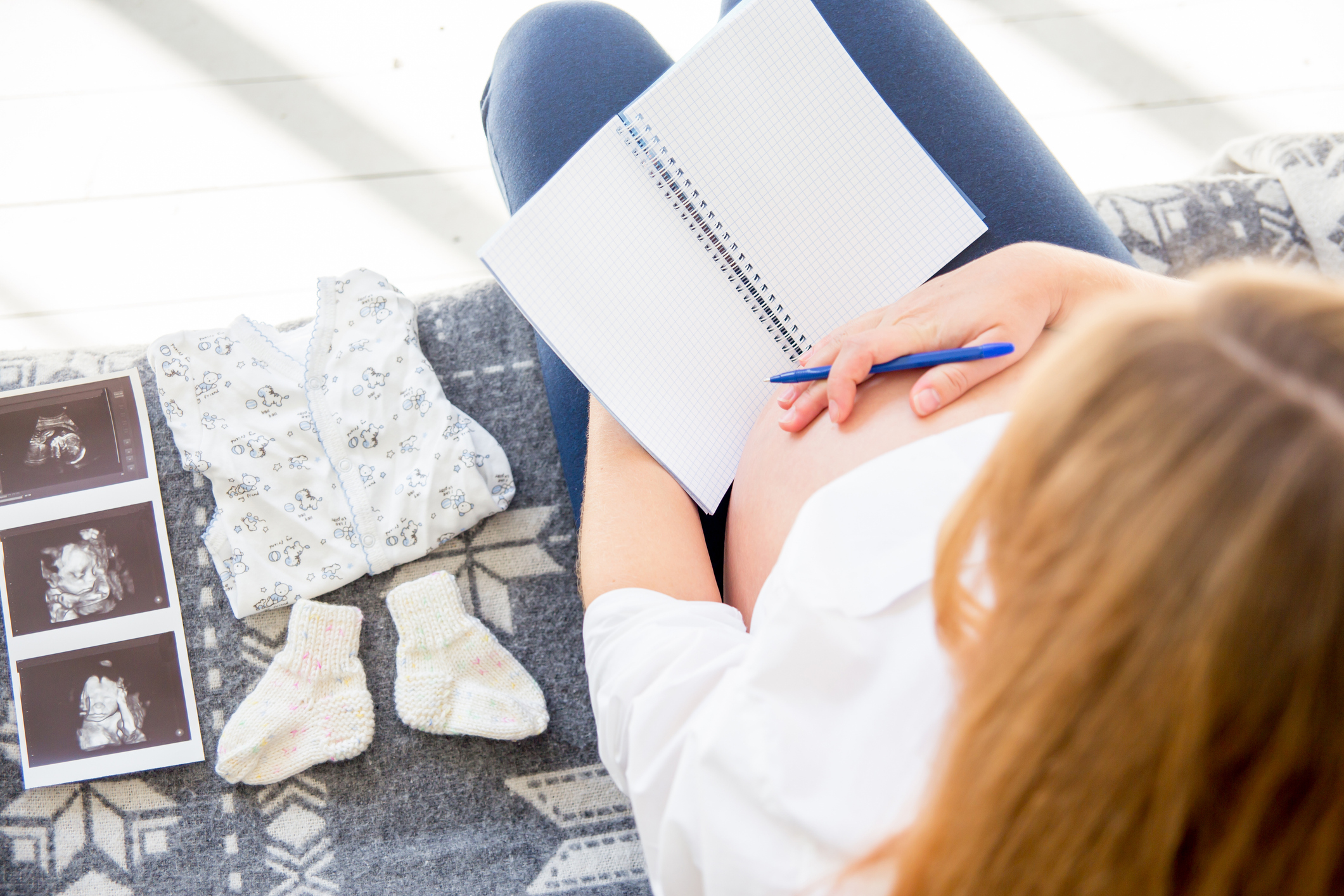 baby registry hacks, tips, and tricks, a portrait of a happy pregnant woman choosing baby clothes for her baby