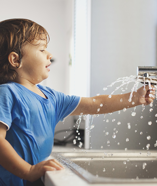 Small boy playing with water in the kitchen