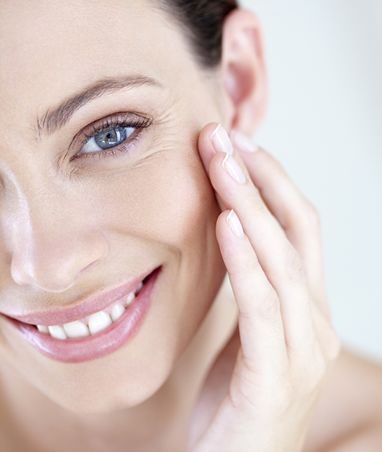 A smiling woman touching her face