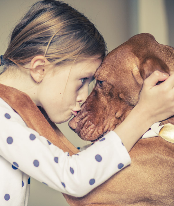 A hug between a young girl and her pet dog A hug between a young girl and her pet dog