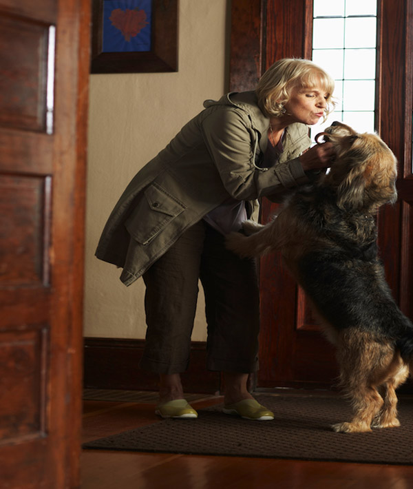 Dog greeting mature woman in entryway of house, side view