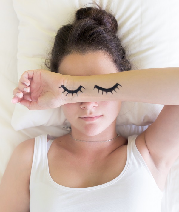 Painted sleeping eyes and brunette young woman in the bed at morning time