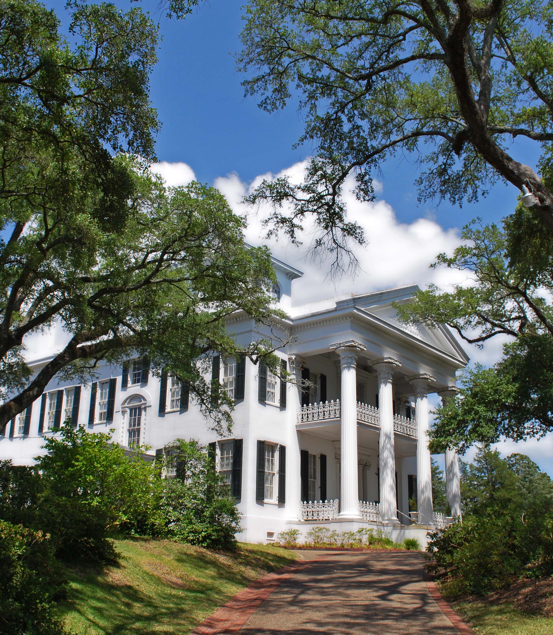 207732-white-columned-antebellum-mansion-framed-by-trees-and-a-s.jpg