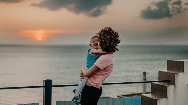 mom-son-hugging-ocean-sunset