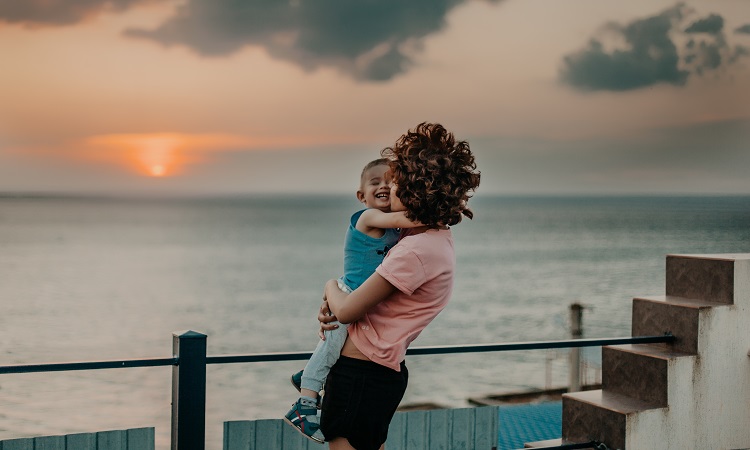 mom-son-hugging-ocean-sunset