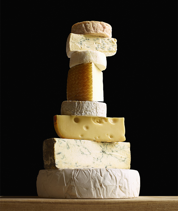 Stack of selection of cheeses, against black background