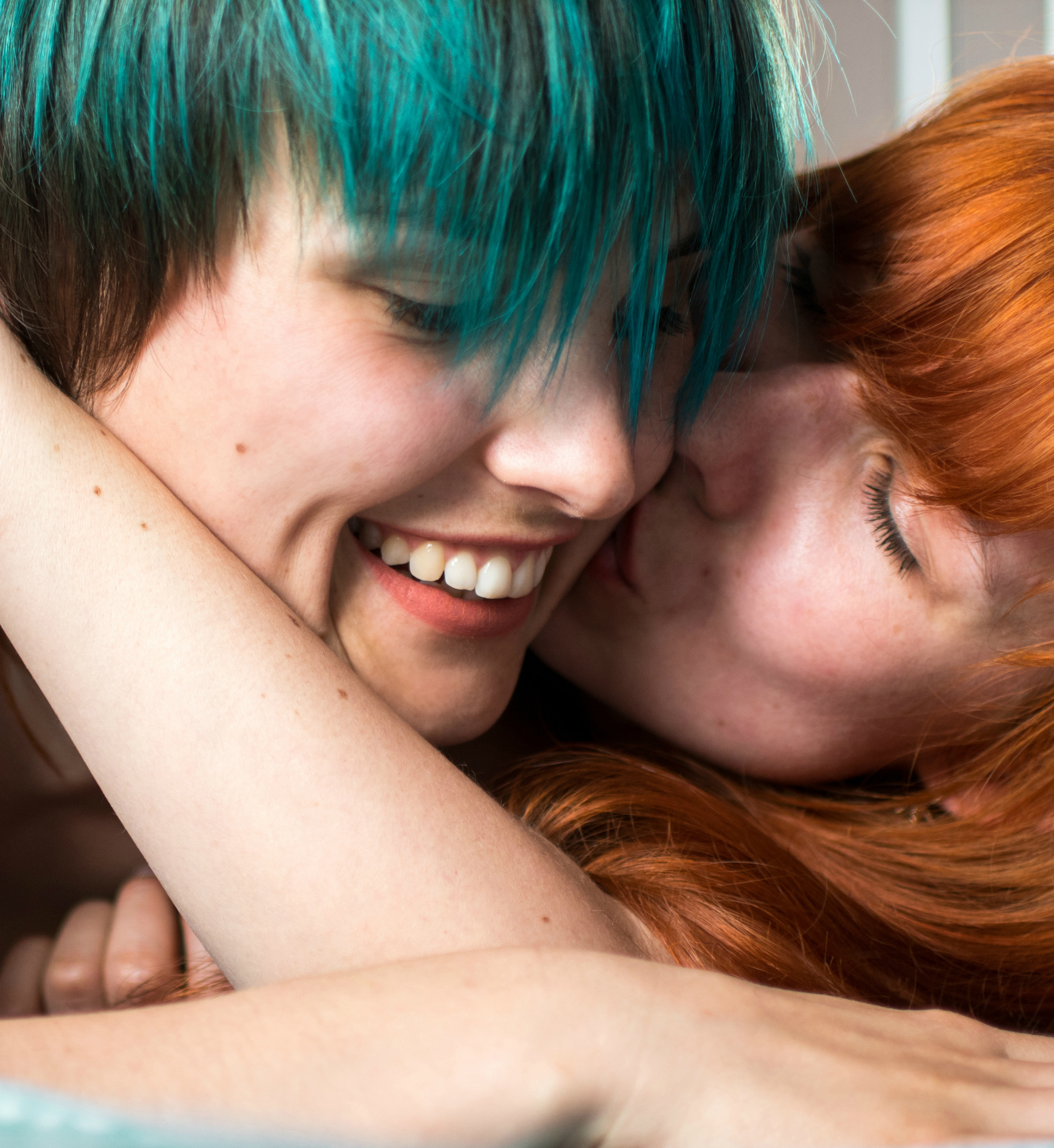 fine portrait with two girls laying on the bed and smile and hugs