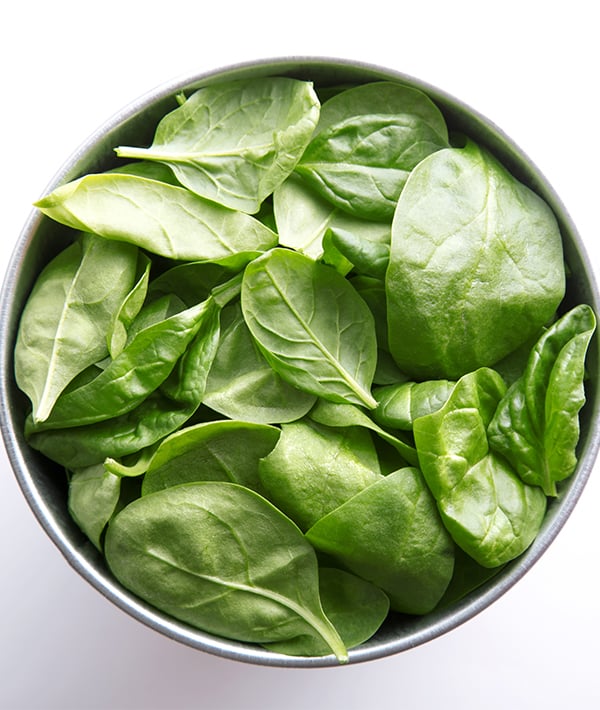 Directly Above Shot Of Spinach Leaves In Container Over White Background