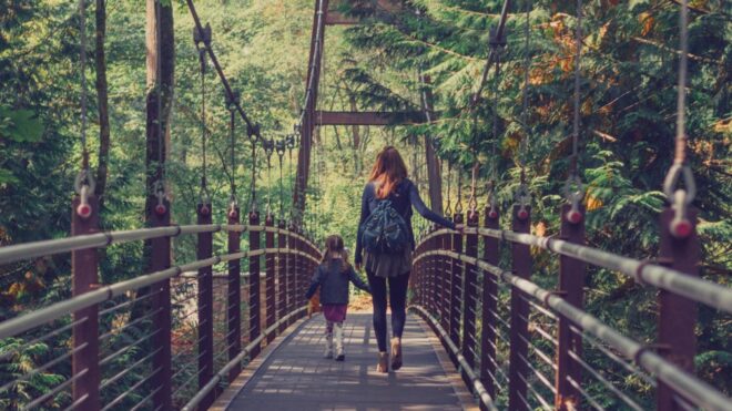 mother-and-daughter-crossing-a-bridge-in-the-woods_t20_2jzlbj