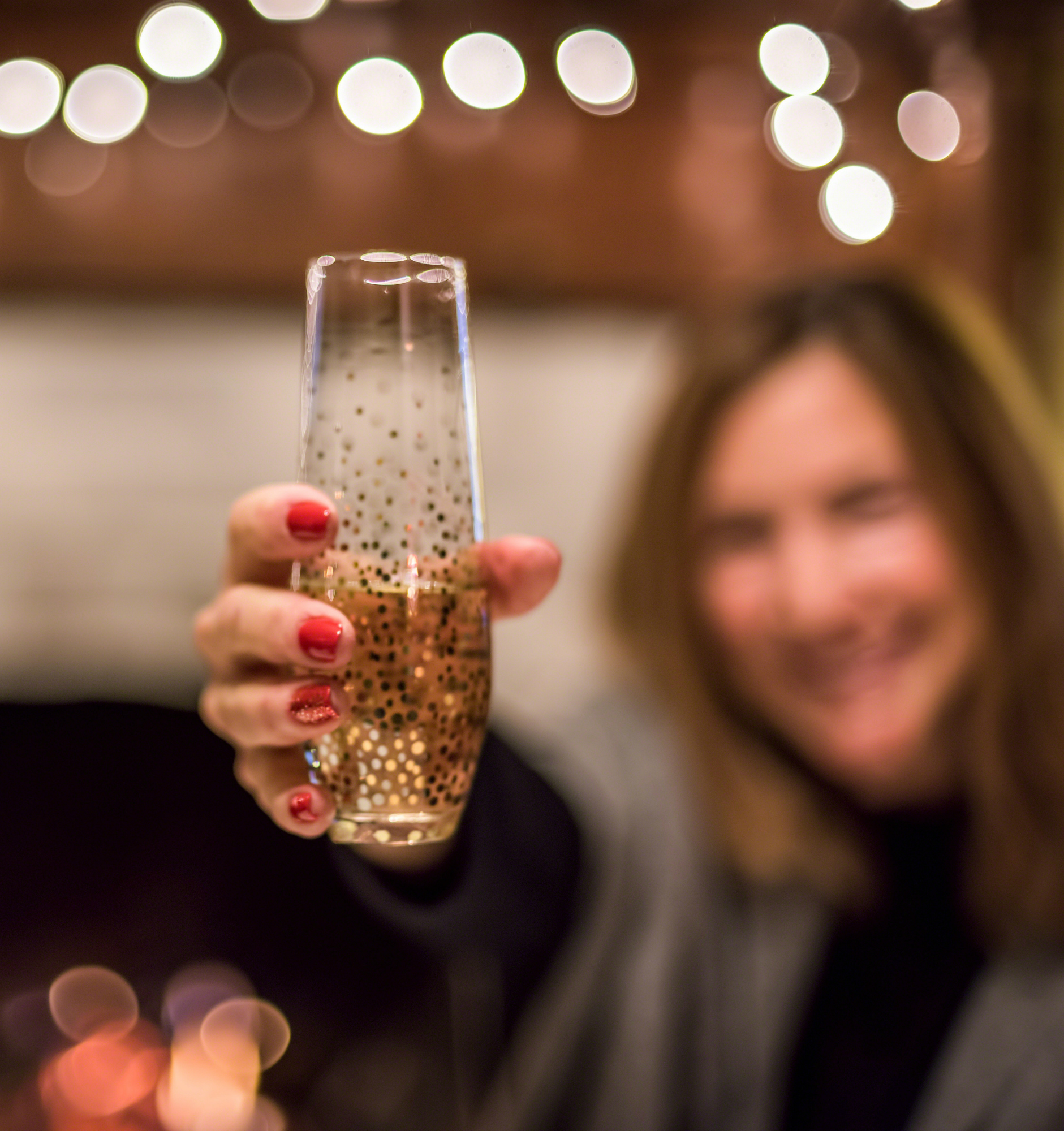 woman holding glass of champagne in front of fireplace on New Year's Eve