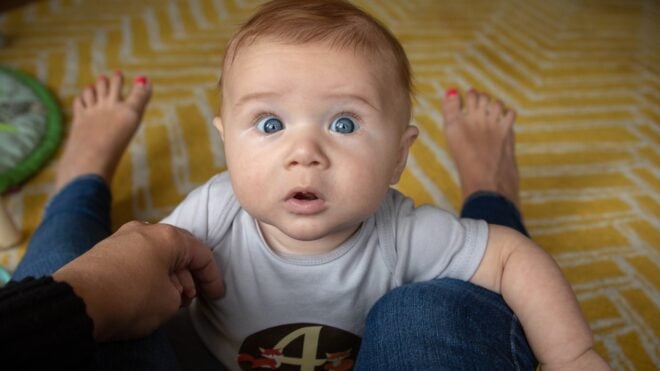 4-month-old-baby-boy-in-between-moms-legs-looking-at-camera_t20_lo9xbo