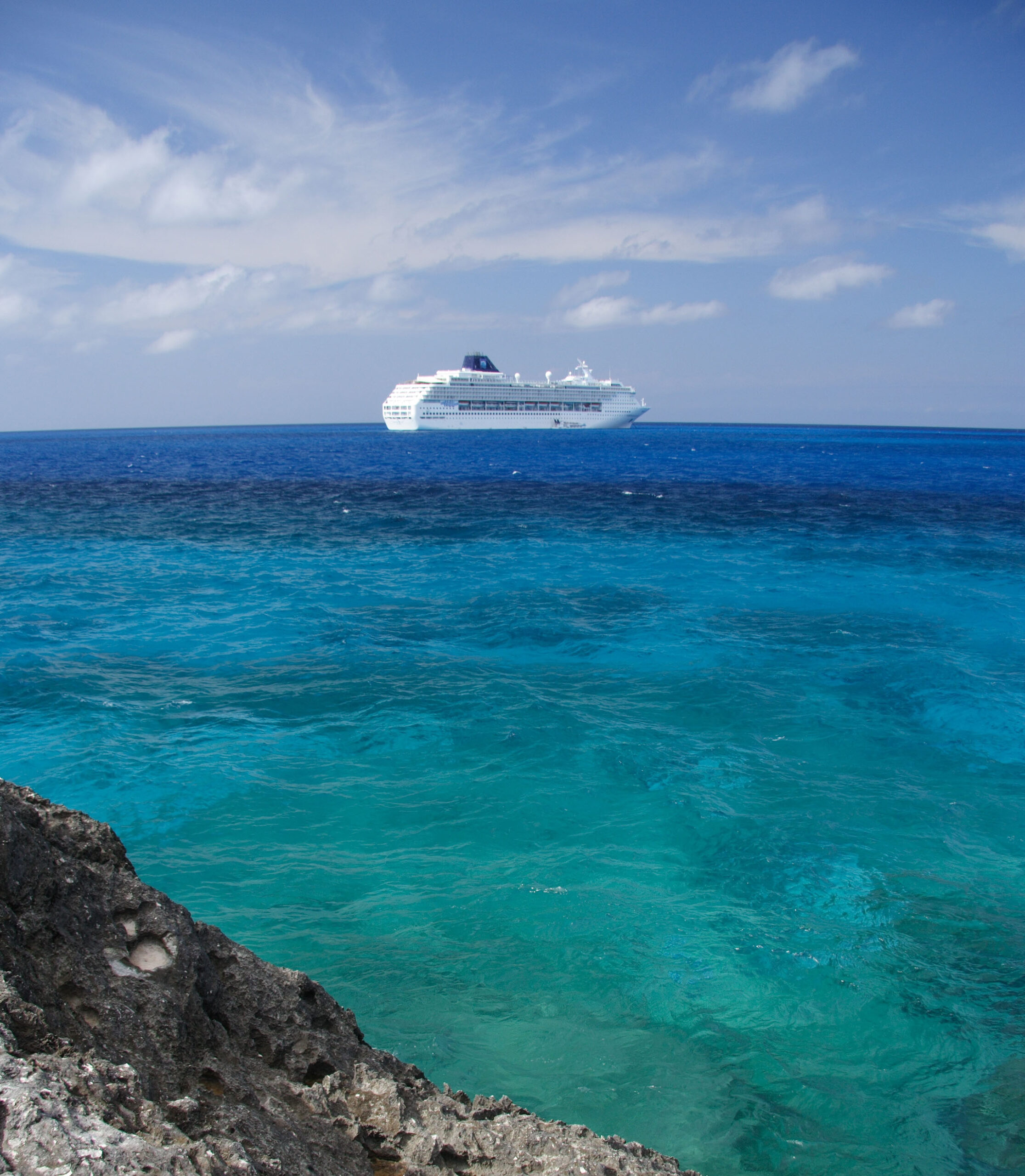 A cruise ship in the distance sails across blue waters