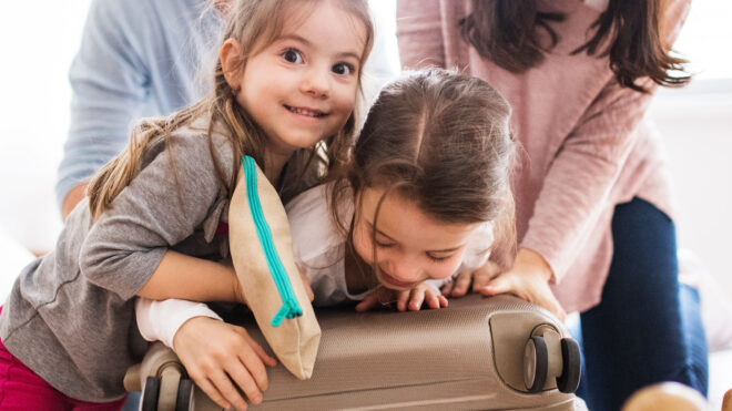 Young family with two children packing for holiday. - Portrait of a young happy family with two children packing for holiday at home.