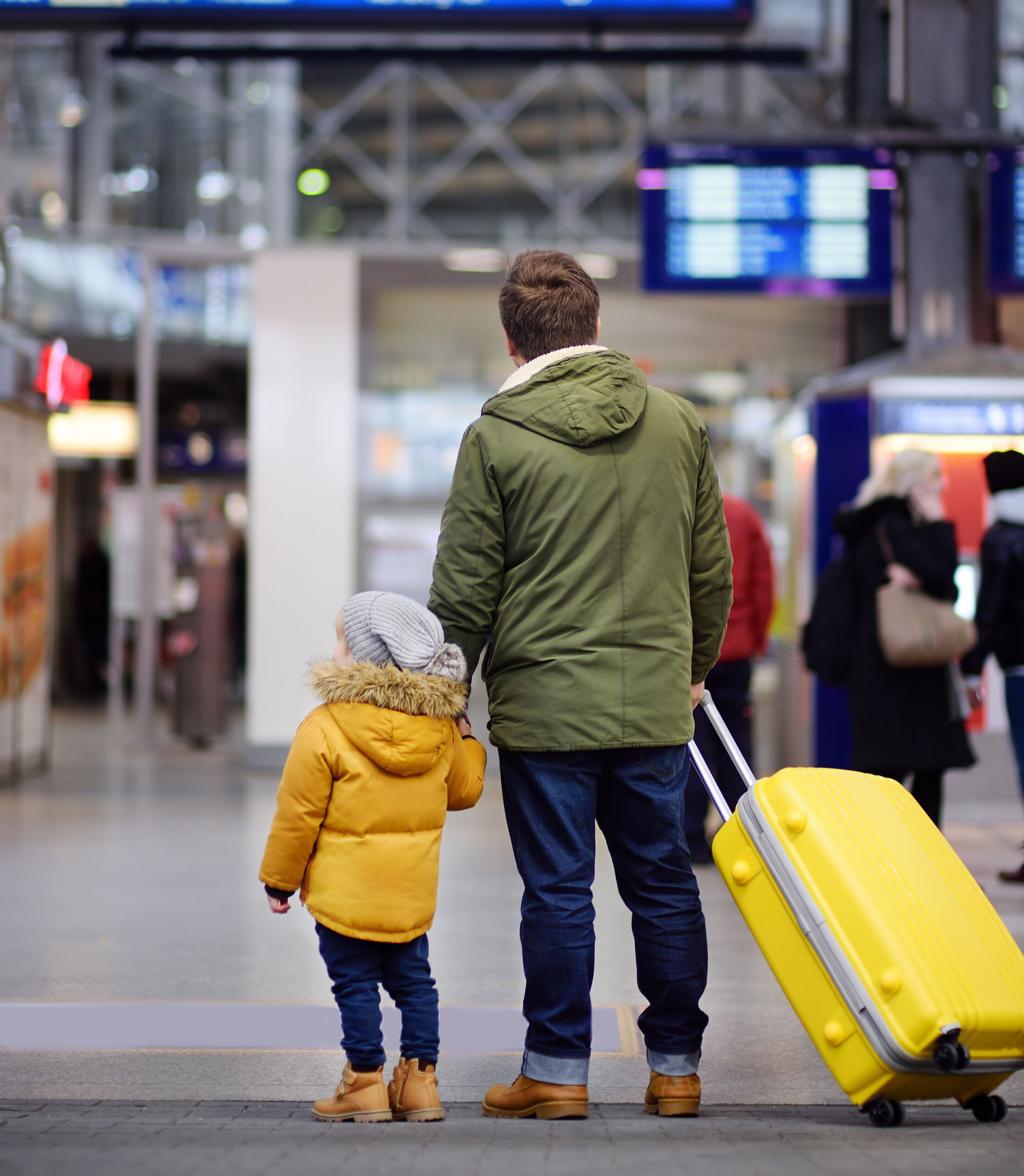 Little boy and his father in international airport or on railway station platform looking on information display