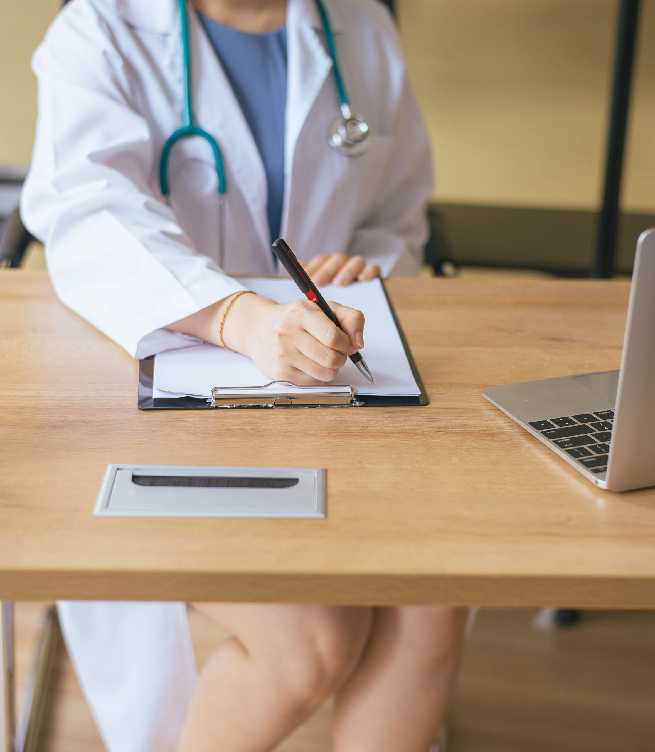 Close up of hands doctor woman writing note with pen on table at hospital