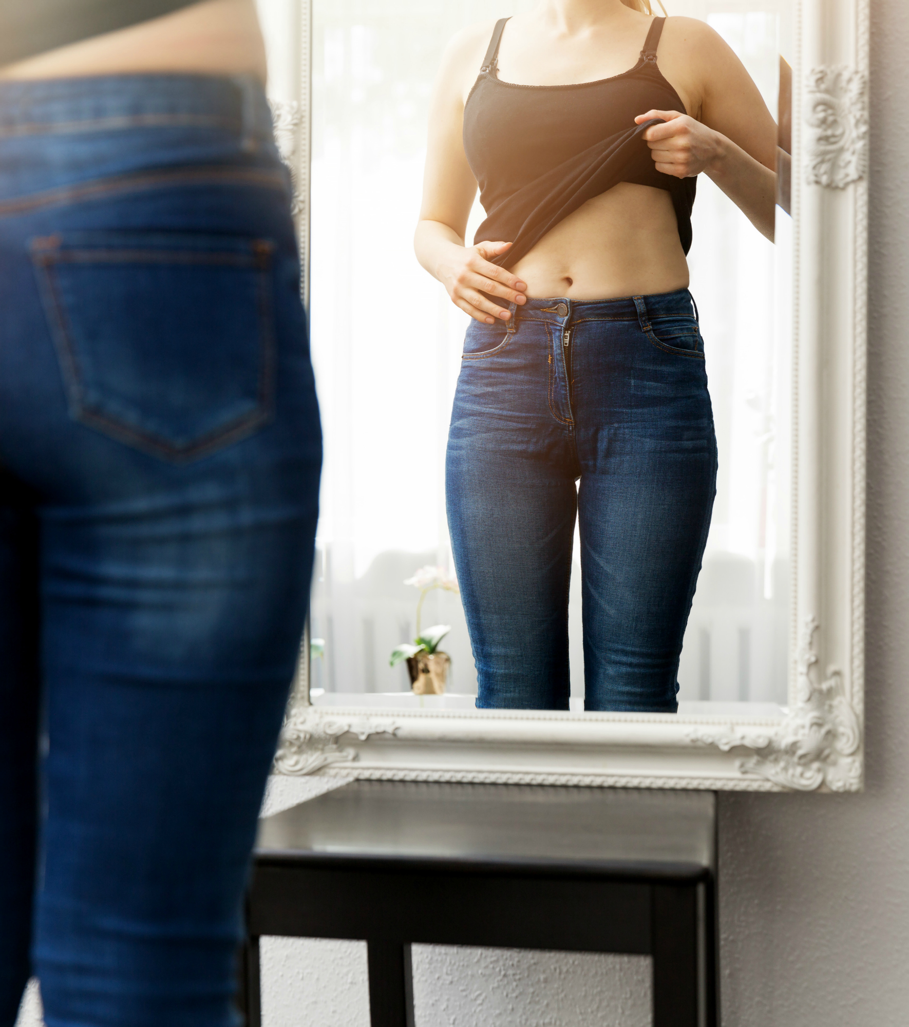 woman checking her body in front of mirror