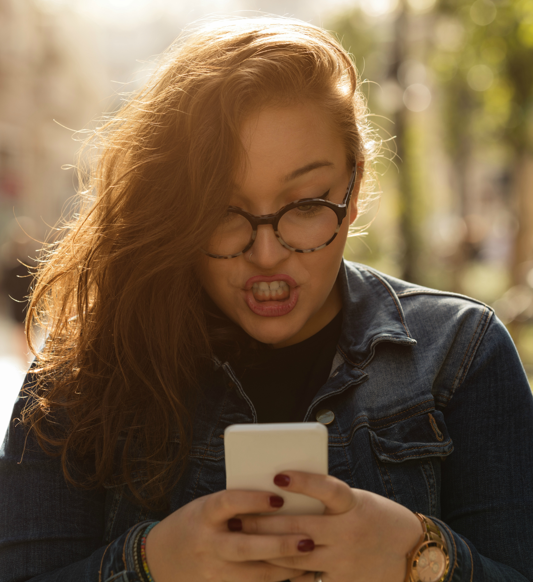 Angry woman using cellphone outdoors.