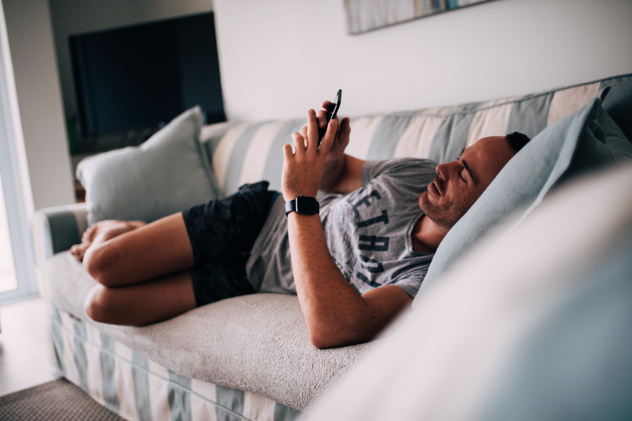 sofa-man-home-smart-phone-couch-laying-down-internet-browsing-mobile-device-smart-watch_t20_xq1aev