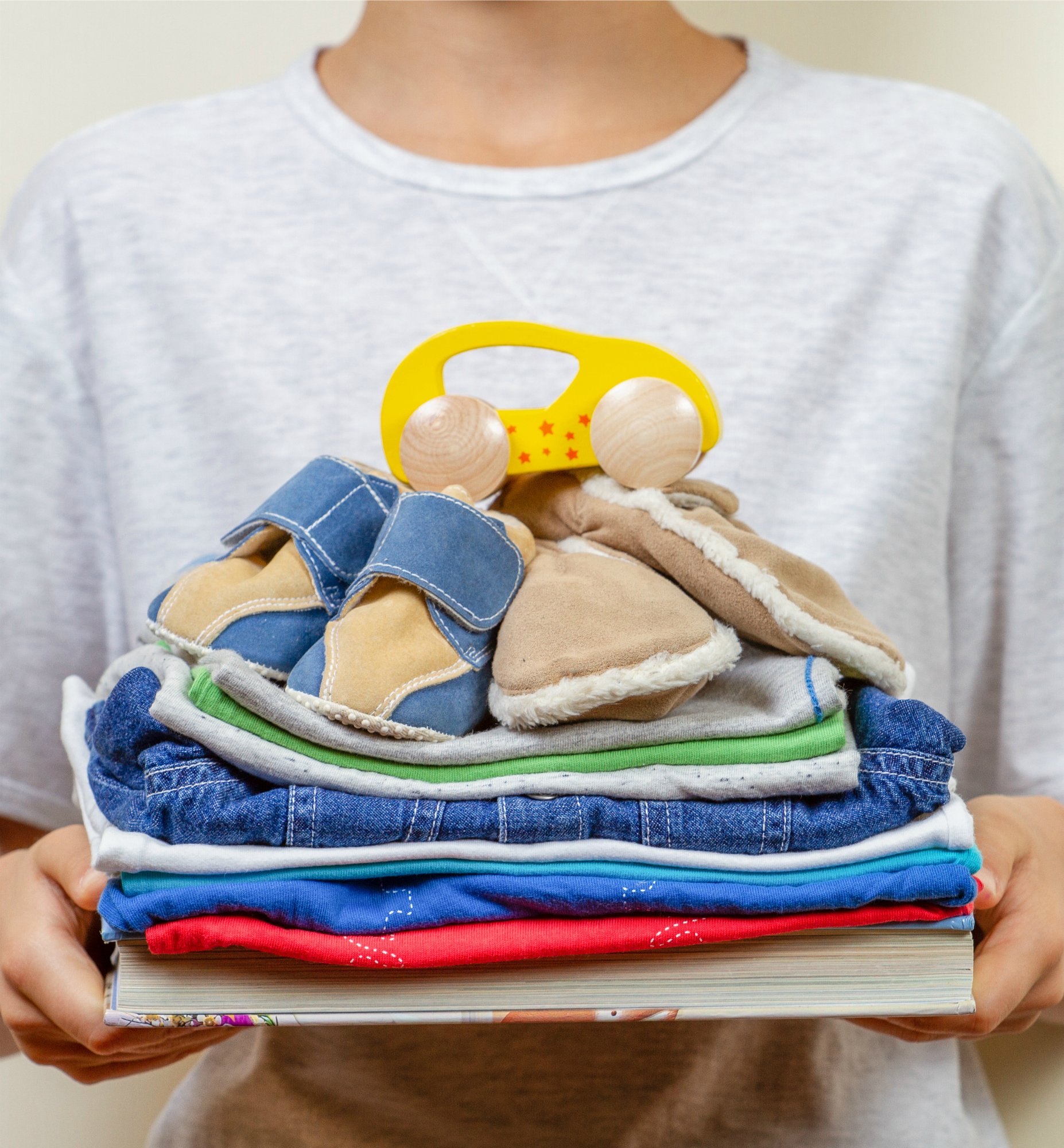 Donation concept. Kid holding in his hands books, clothes and toys for charity.