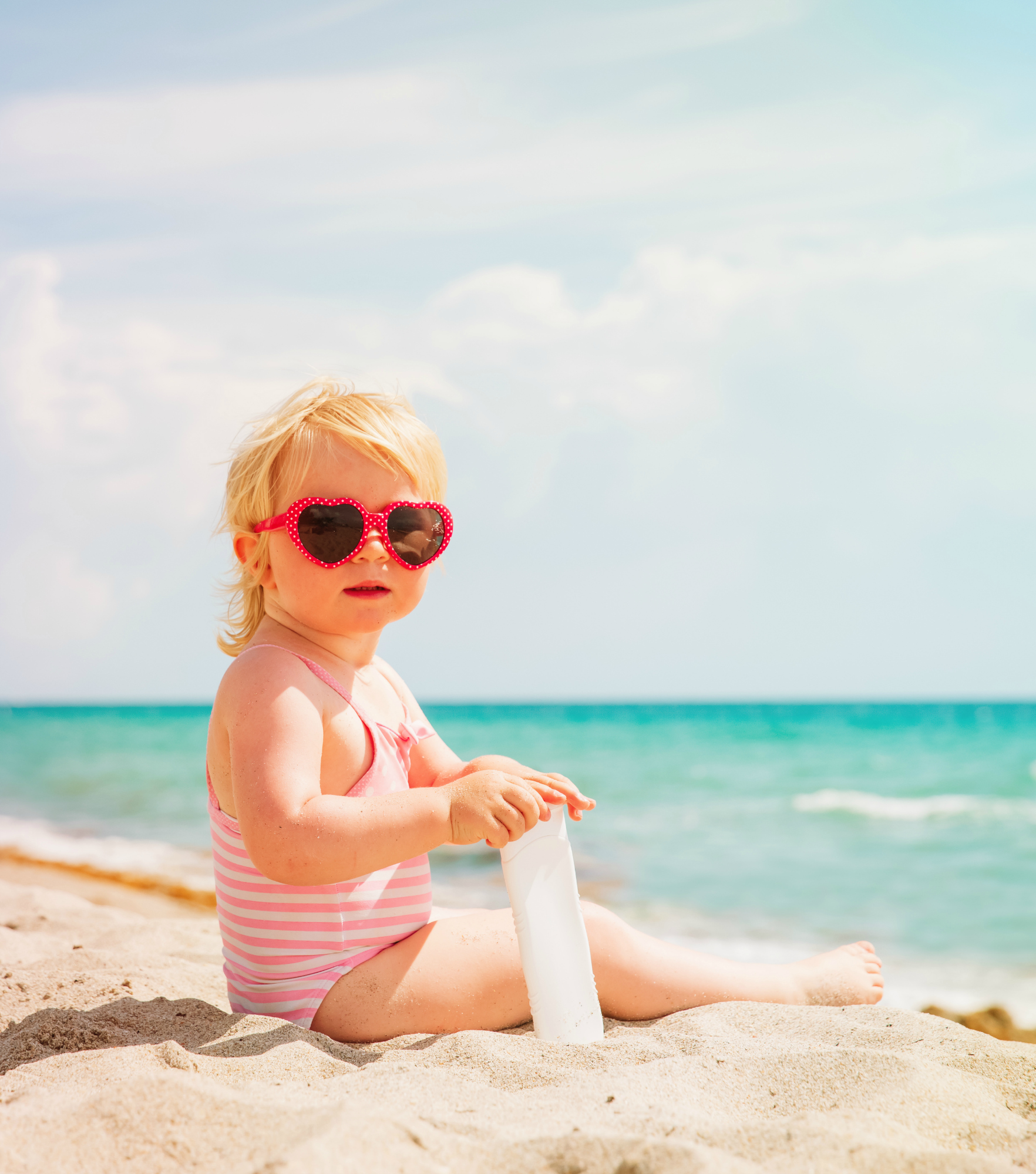 cute little girl with sunblock cream on tropical beach, sun protection