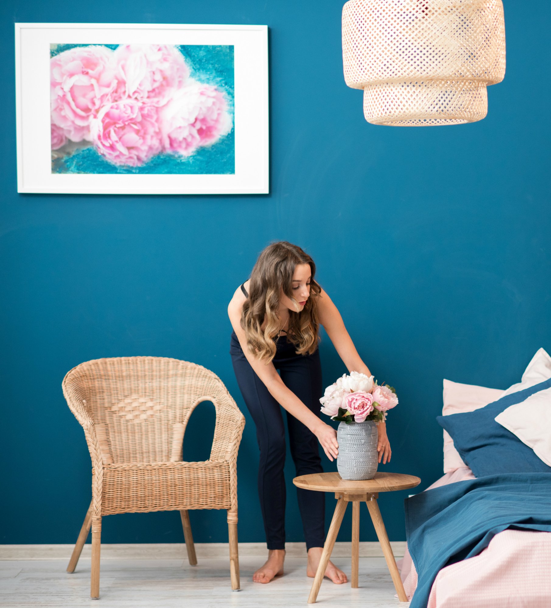 Young woman decorating bedroom with beautiful flowers at home