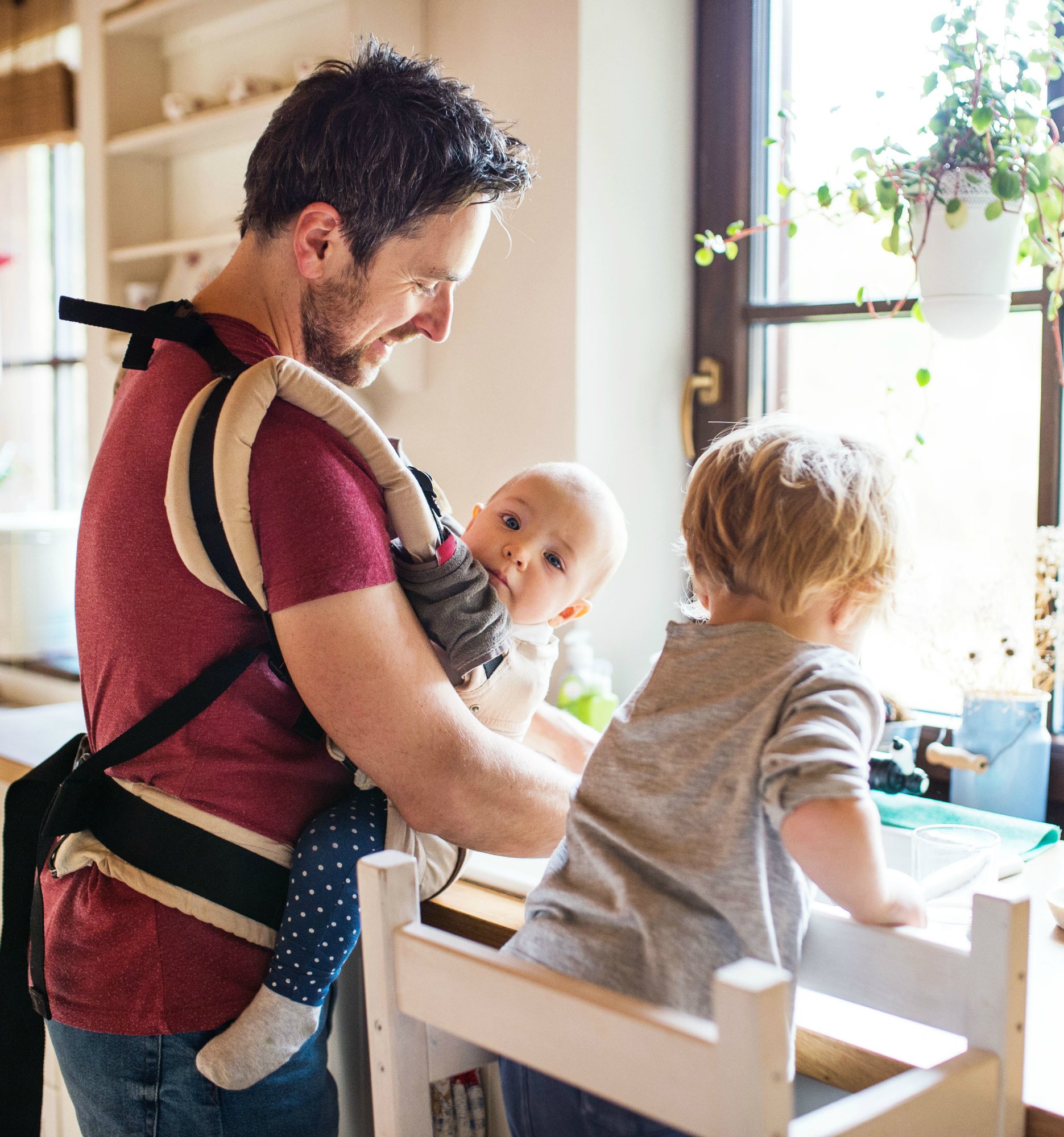 Handsome father and two toddlers washing up the dishes.