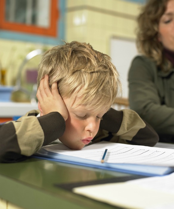 Mother and son (5-7) at table (focus on boy resting chin on homework)