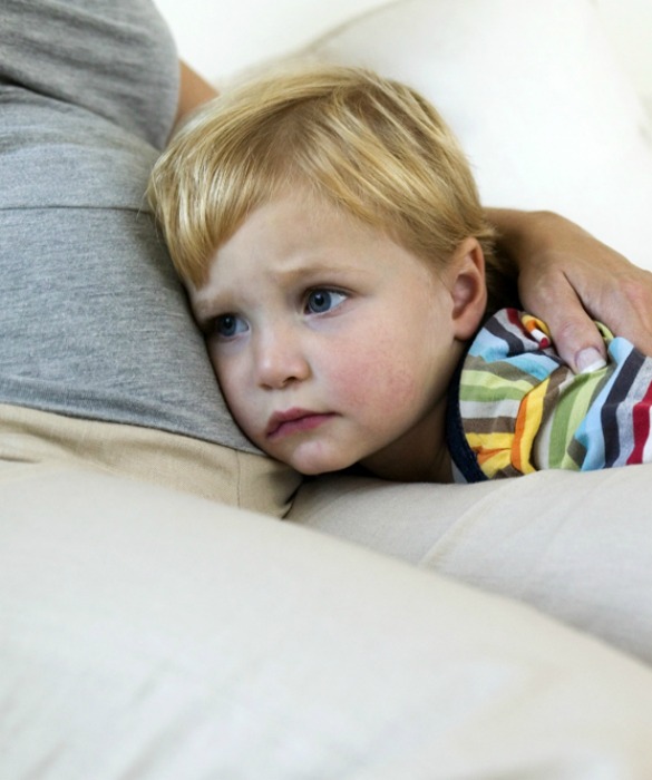 Boy resting his head on pregnant woman's belly, close-up