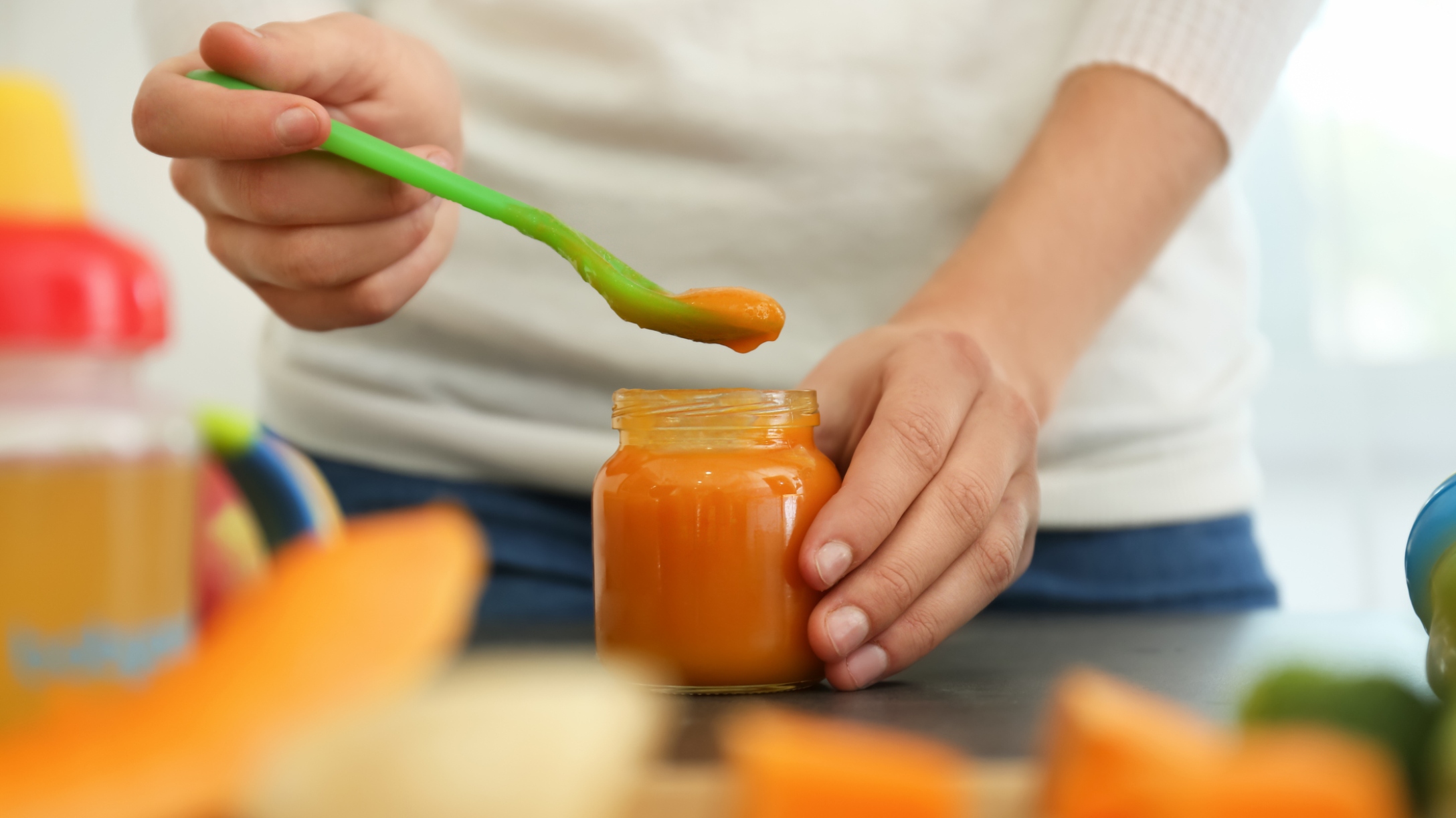 Mom scoops baby food from a jar