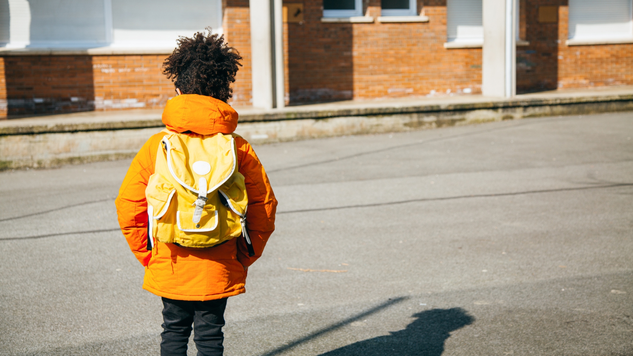 Young Black child stands in a courtyard alone