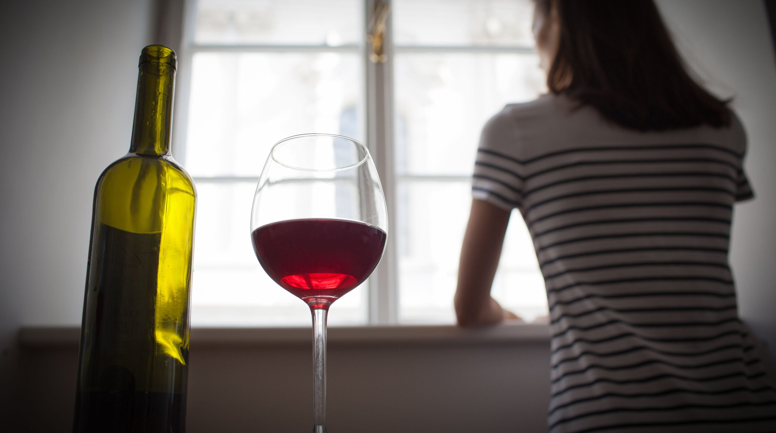 Woman drinking wine alone in the dark room