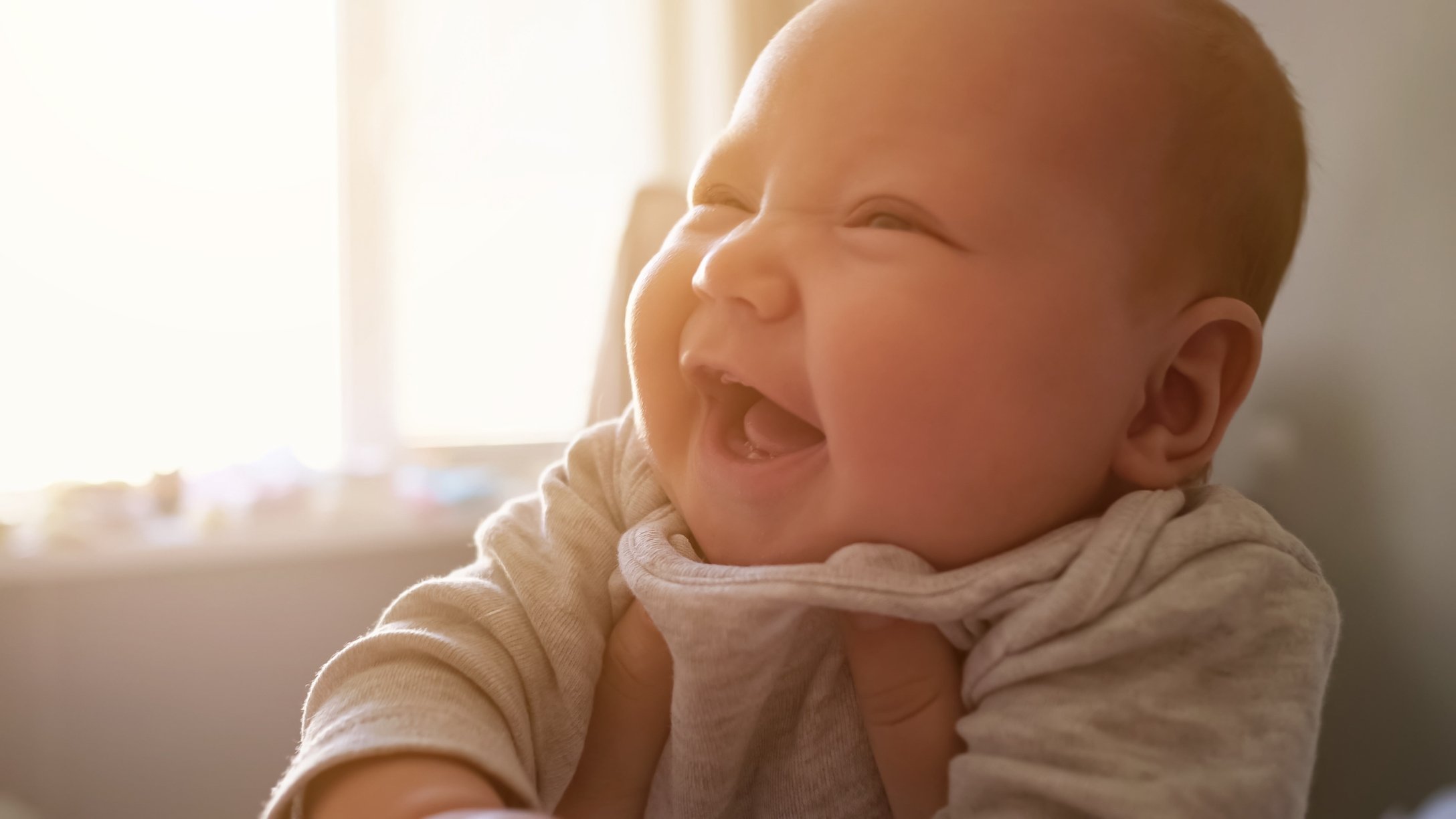 Baby being held up gives a big smile