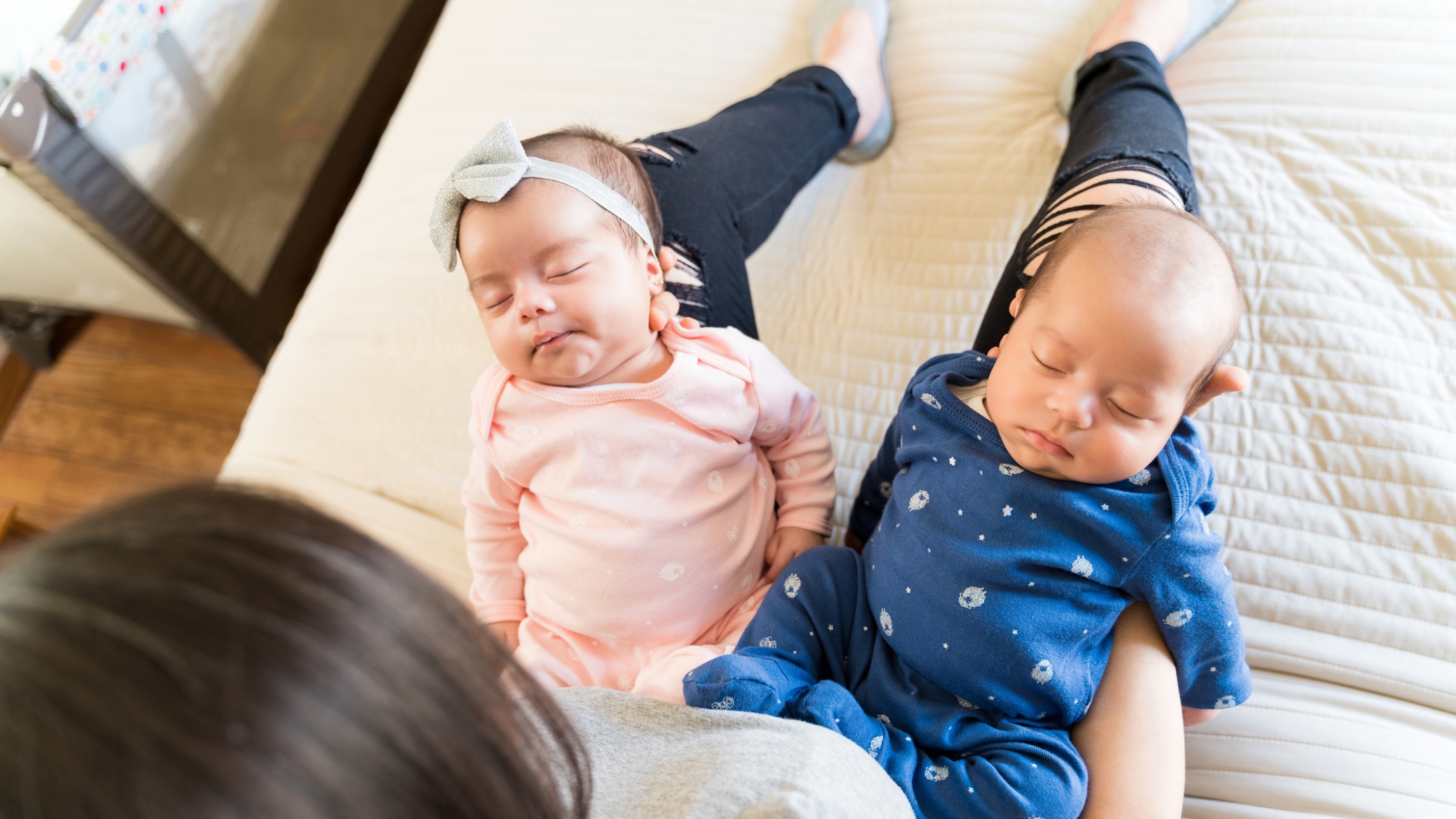 Tired mom holds two newborns in her arms