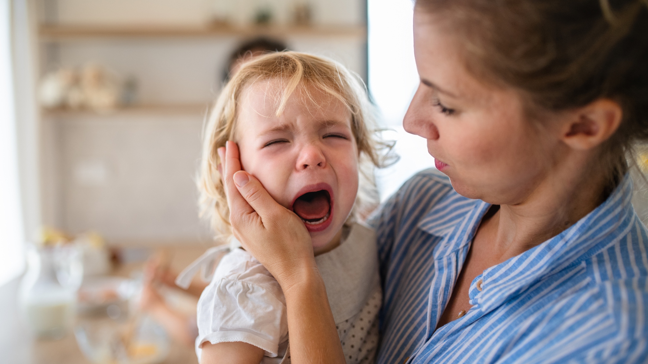 Mom holds crying toddler mid-tantrum