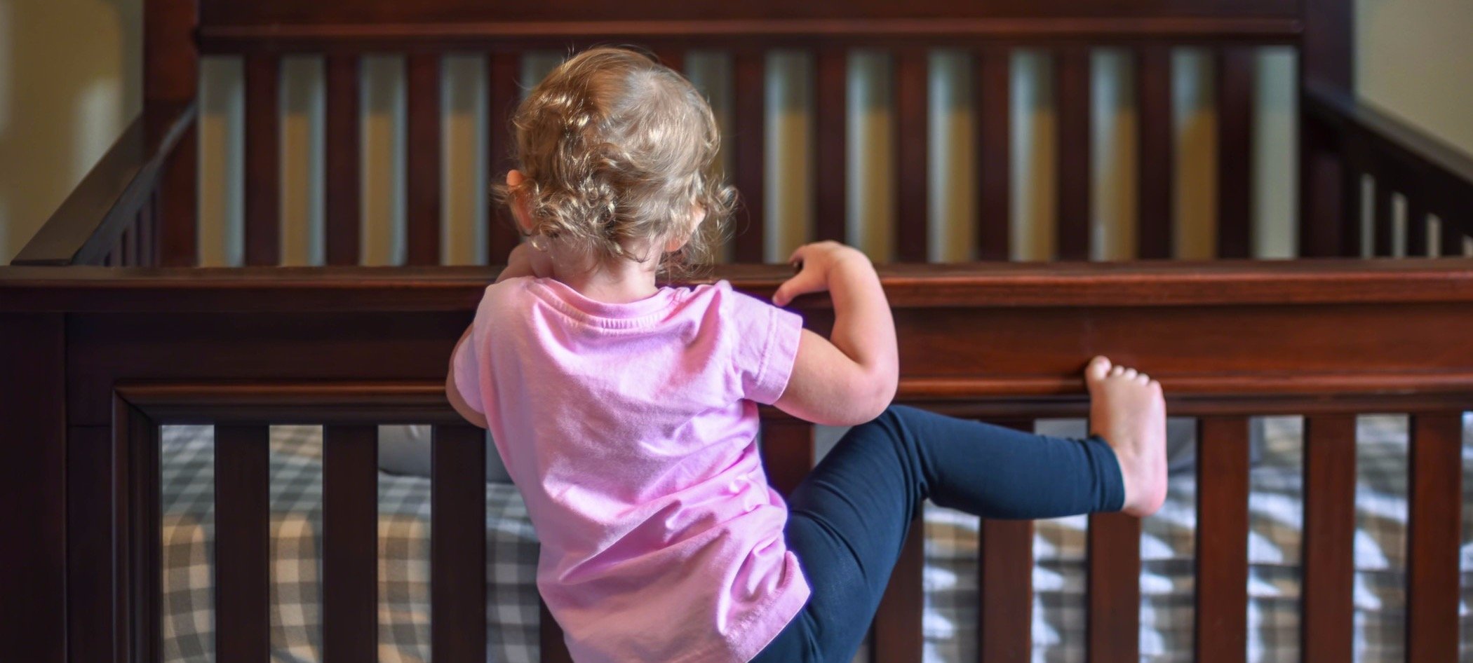 Toddler climbing on crib