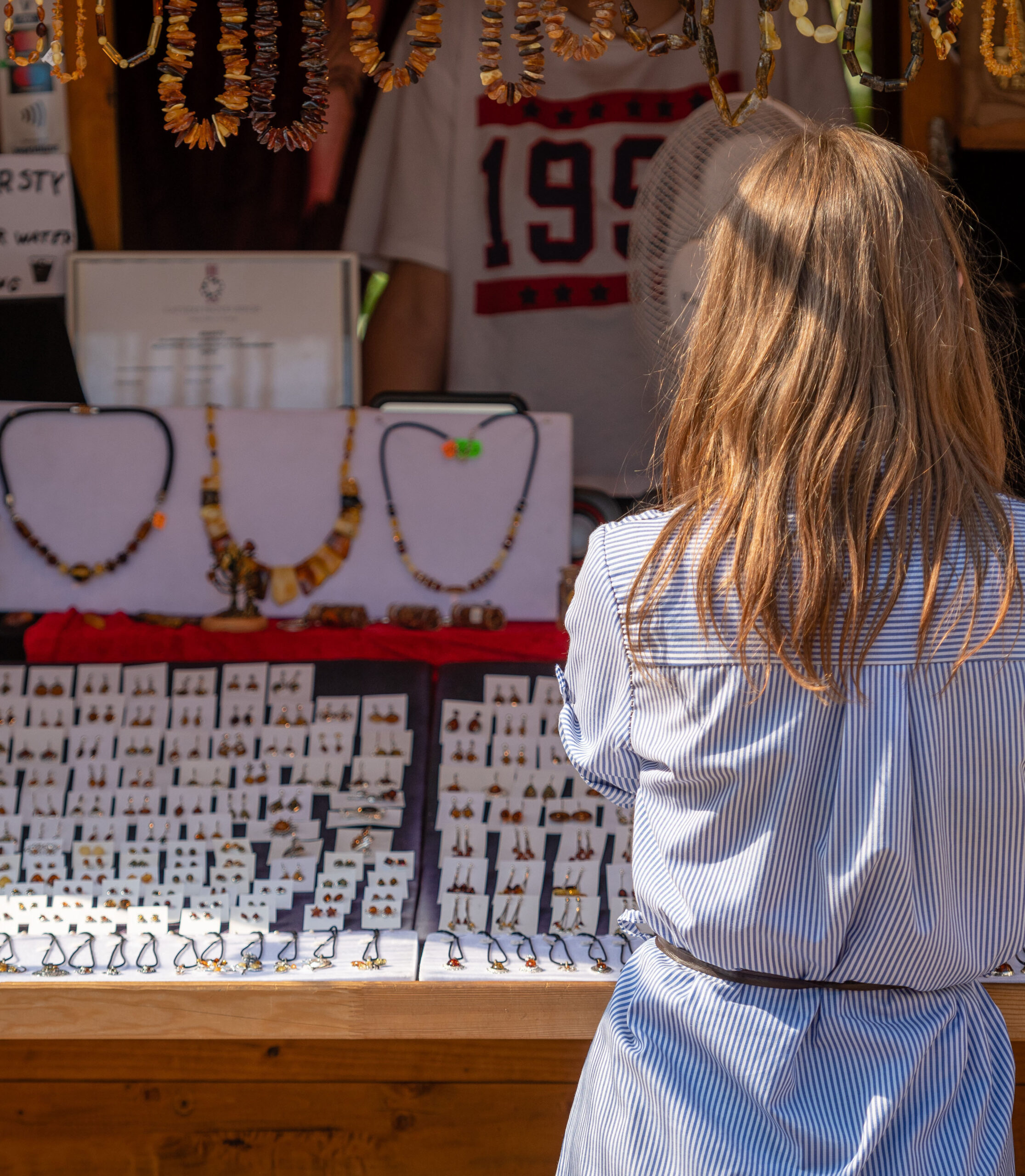 A woman in the souvenir kiosk choose amber jewelry.