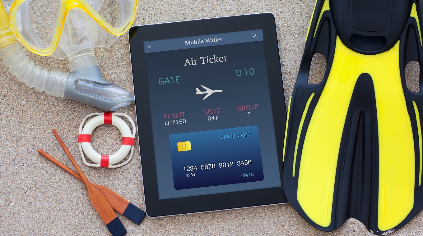 tablet with computer with online air ticket lying on sand