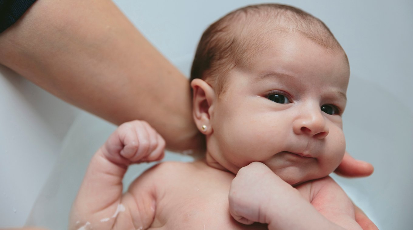 Newborn in the bathtub held by her mother
