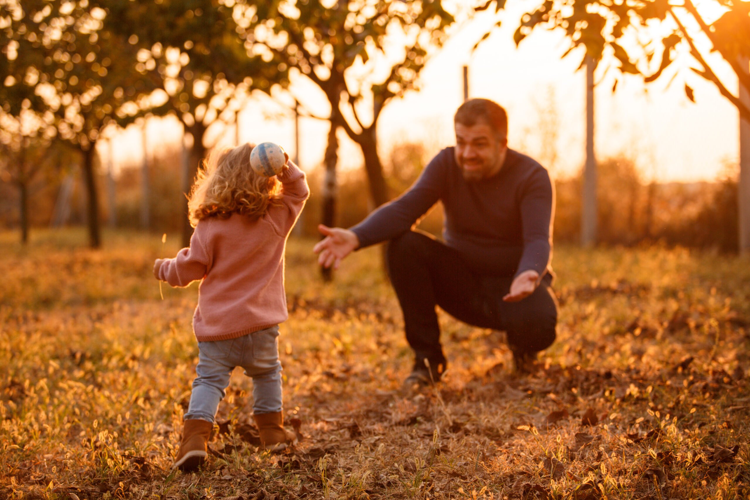 Father playing catch with his toddler daughter at the park