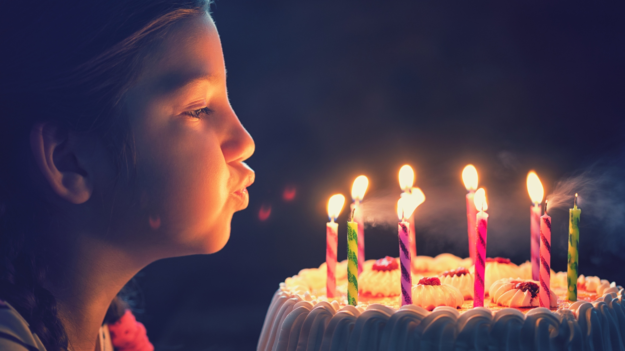 Little girl blows out birthday candles on cake