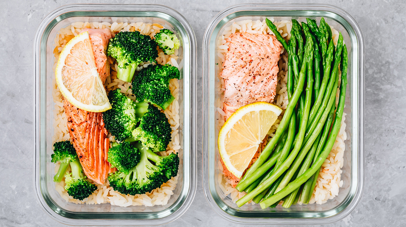 Meal prep lunch box containers with baked salmon fish, rice, green broccoli and asparagus