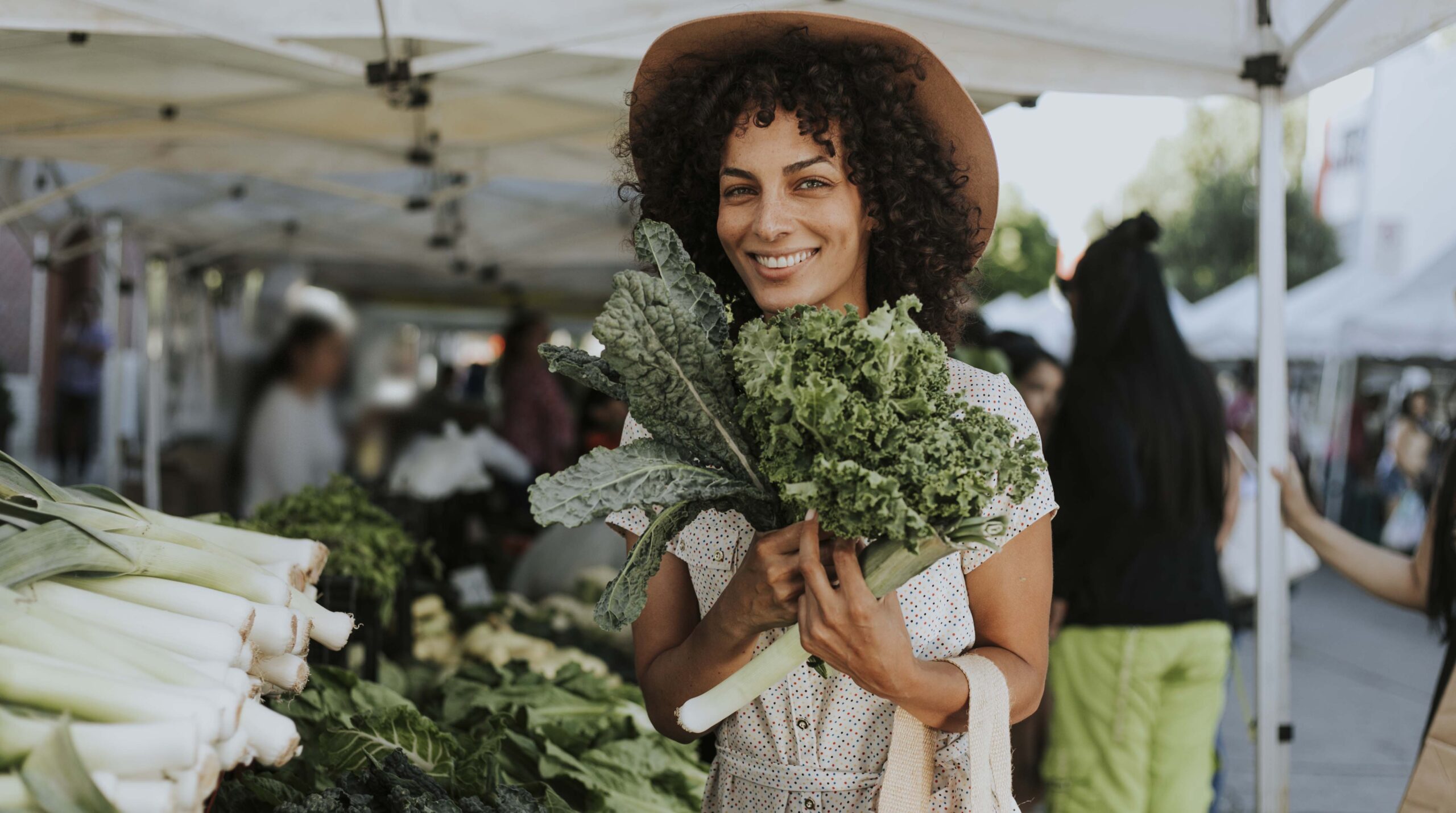 Beautiful woman buying kale at a farmers market
