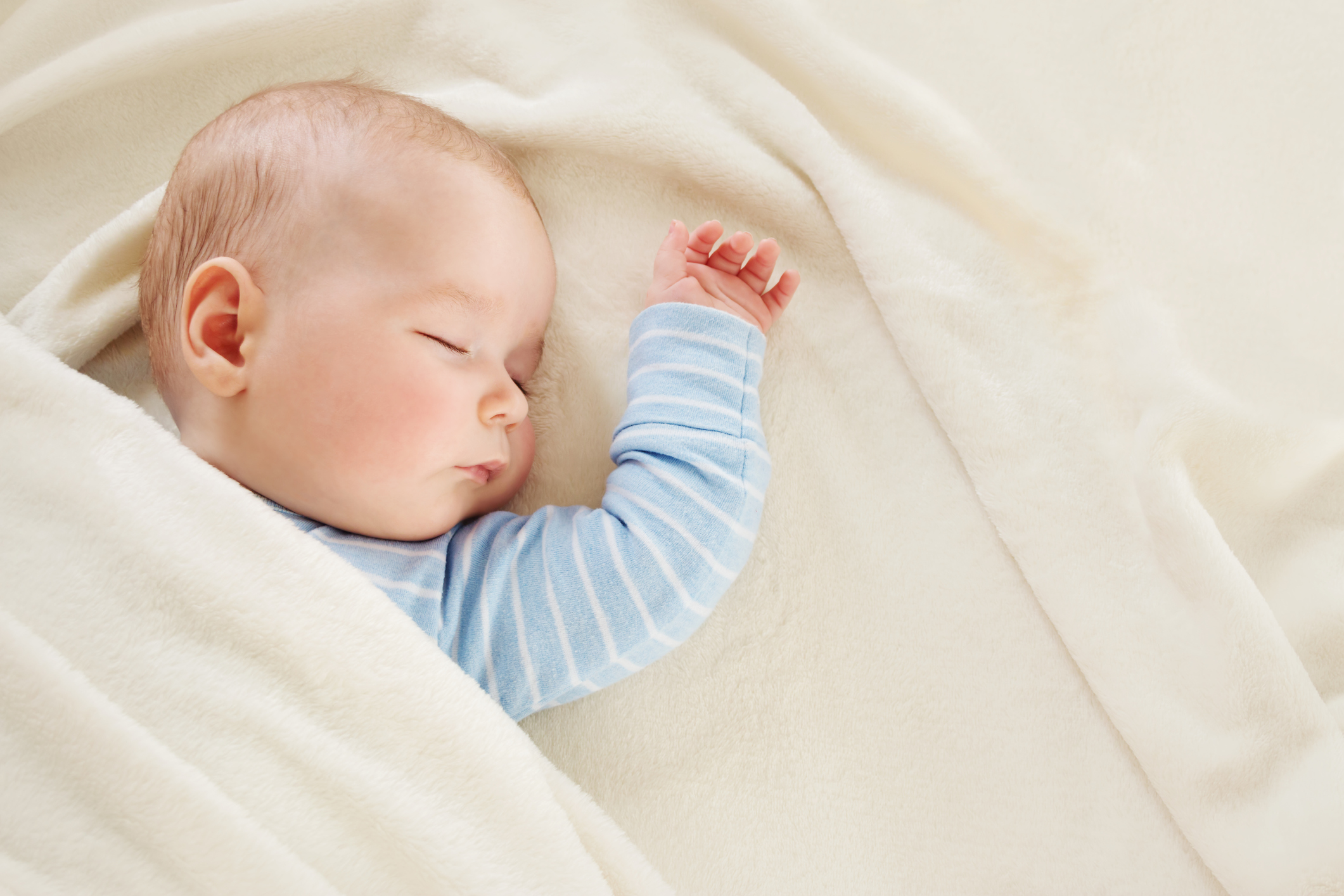 Baby sleeping covered with soft white blanket