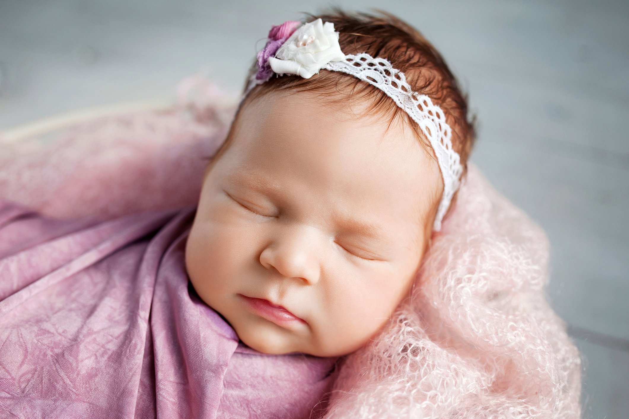 Sweet newborn baby sleeping. Newborn girl 3 weeks old lying in a basket with knitted plaid. Portrait of pretty newborn girl. Closeup image