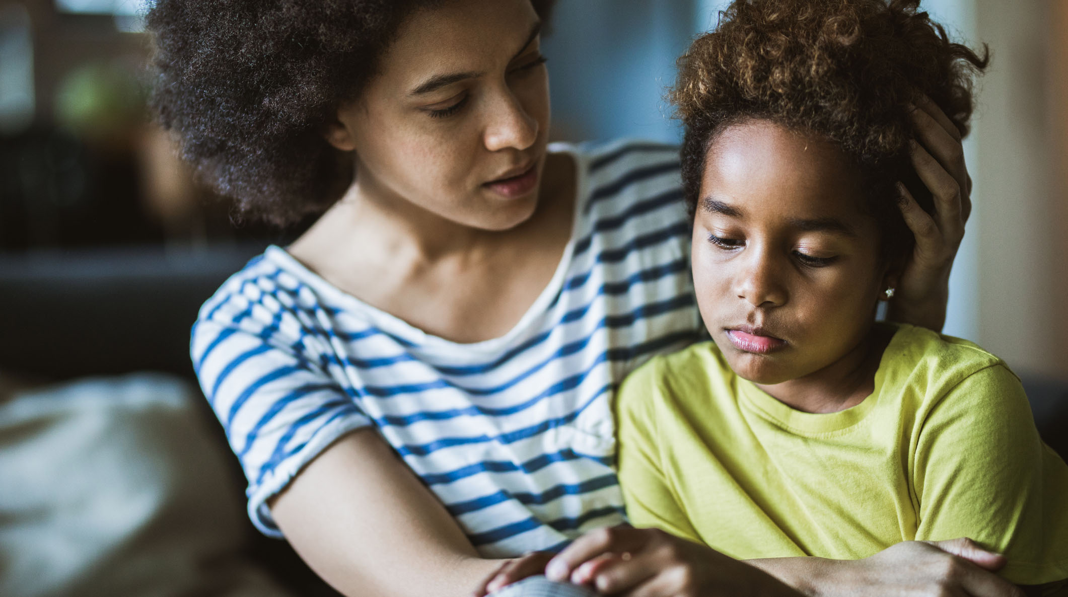 African American mother consoling her sad girl at home.