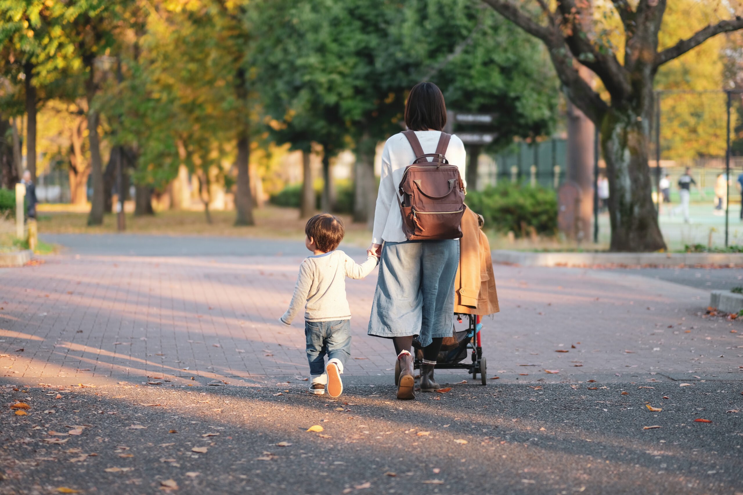 Mother and son walking in park with holding hands